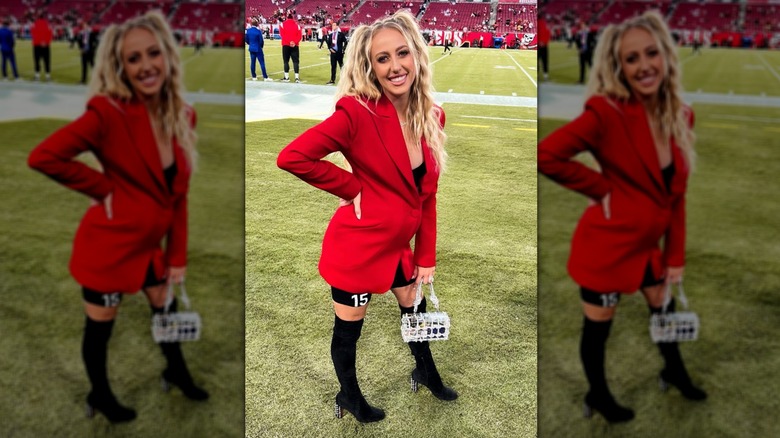 Brittany Mahomes with a red blazer and black tall boots on the field