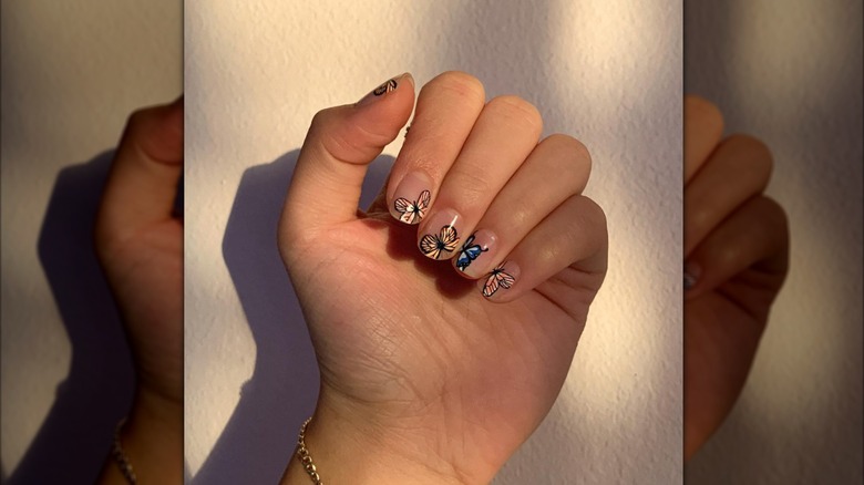 Woman's curled hand with butterfly nail art