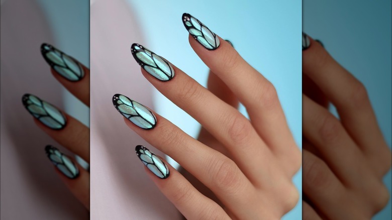 A hand with blue shimmering butterfly wing nails