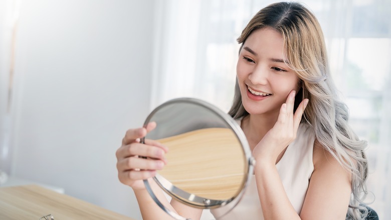 Happy woman admiring skin in mirror