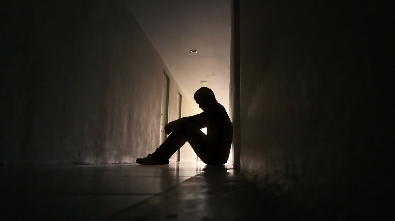 Person sitting in a dark hallway