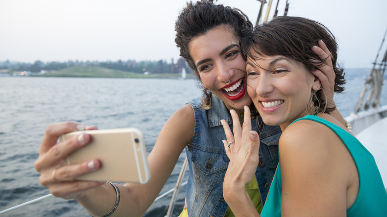 Lesbian couple taking an engagement selfie on a boat