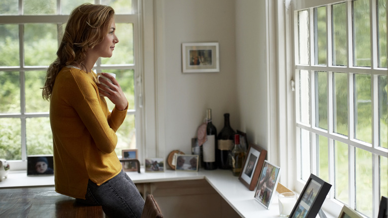 Woman holding coffee mug and staring out the window