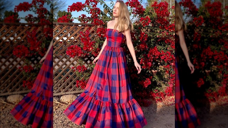 A woman walking outside with a cherry red plaid dress