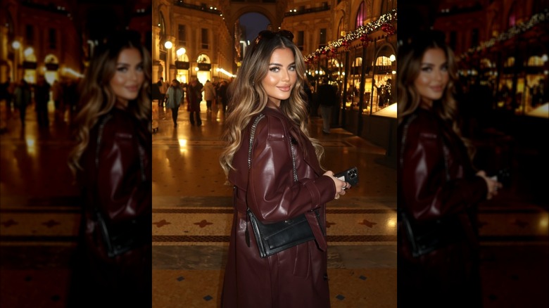 A woman standing outside with a cherry red leather coat on and long hair