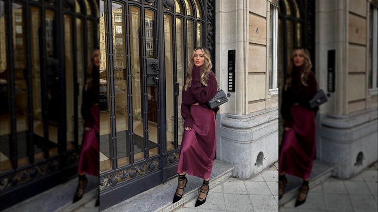 A woman standing outside in a cherry red skirt and sweater