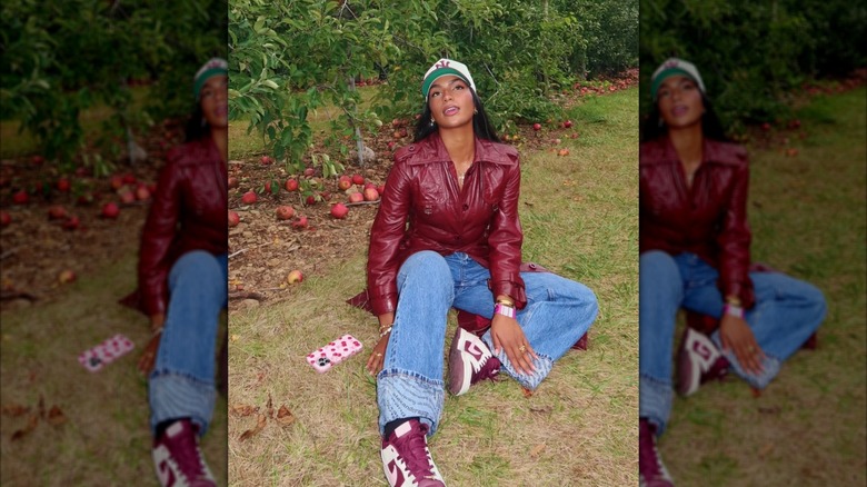 A woman on Instagram wearing a cherry red coat, jeans, red shoes and a hat by apples