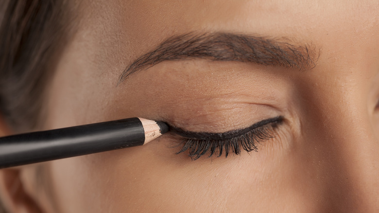 woman drawing eyeliner with pencil