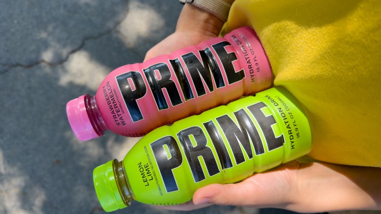 Person holding two bottles of Prime hydration drinks