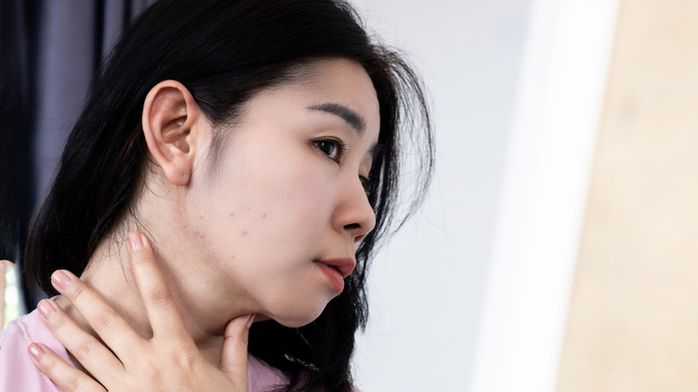 Woman looking at jawline in mirror