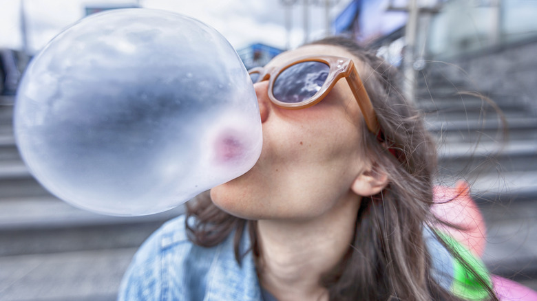 Person chewing gum blowing a huge bubble