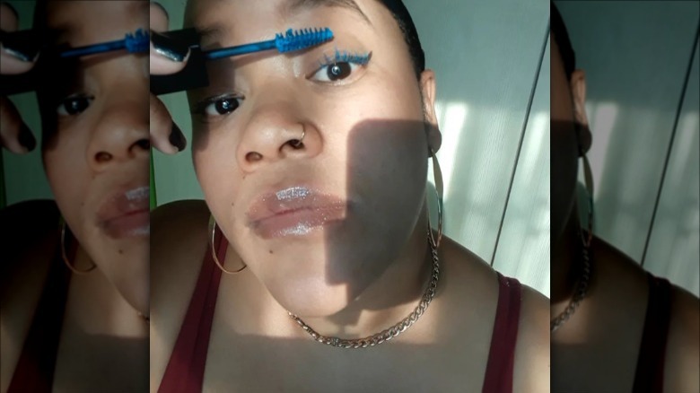 Person applying blue mascara