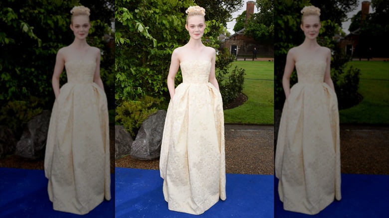 Elle Fanning wearing a yellow gown and flowers in her hair at a "Maleficent" event