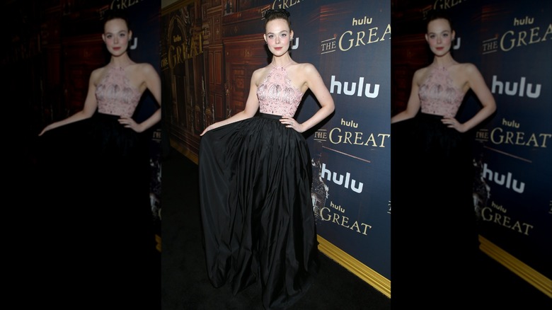 Elle Fanning holding out her black skirt at the premiere of "The Great" in 2021