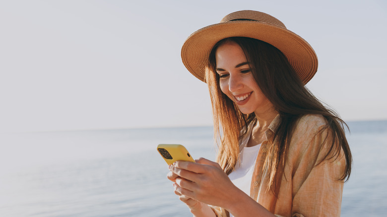 woman wearing straw hat and texting