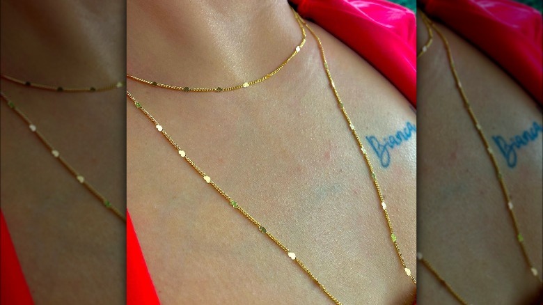 Person wearing two gold necklaces