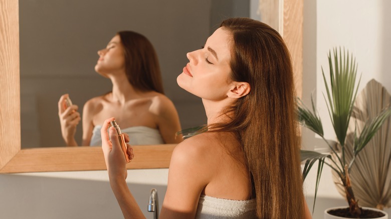 Woman applying perfume to neck 
