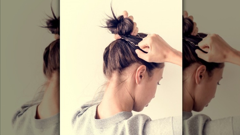 woman putting hair in bun