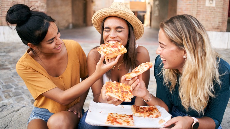 Friends feeding each other pizza