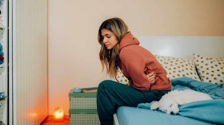 Woman with cramps sitting on her bed