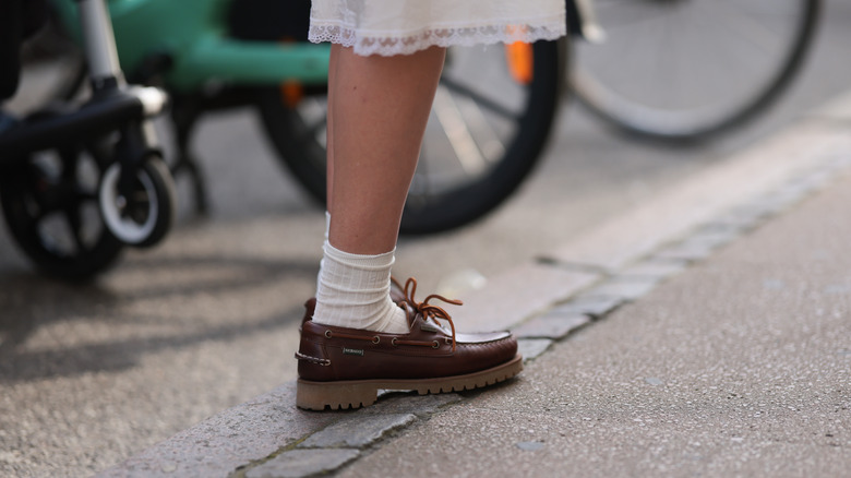 Close-up of leather boat shoes worn with high socks and a lace-trimmed skirt