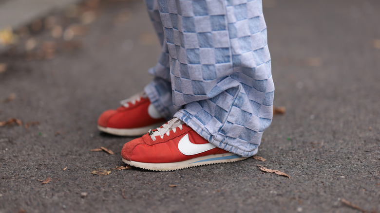 Close-up of red Nike Cortez sneakers worn with patterned jeans