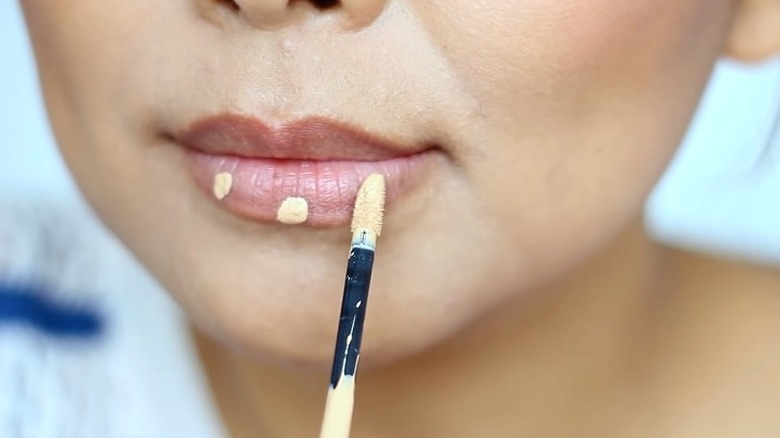 woman applying foundation on lips