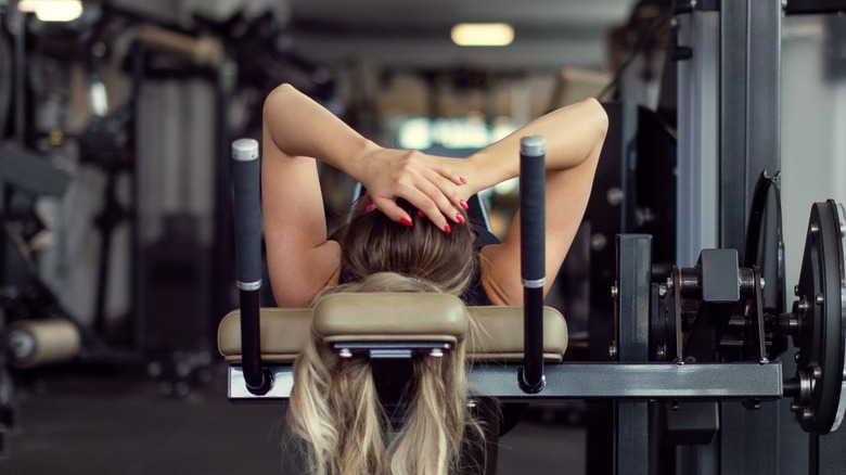Woman exhausted and laying down on gym equipment with hands on her head