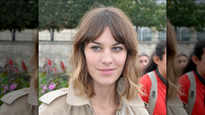 Alexa Chung with curtain bangs and a fringe haircut, wearing a trench coat