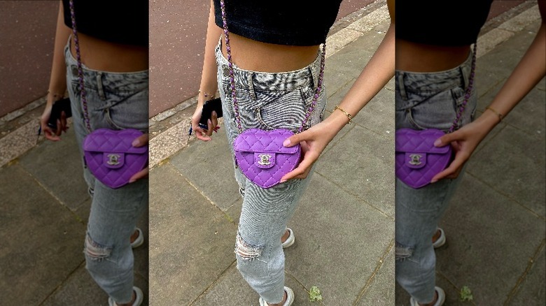 Person posing on sidewalk with purple heart-shaped purse