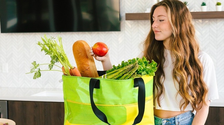 Model with green and yellow Rareform tote full of groceries