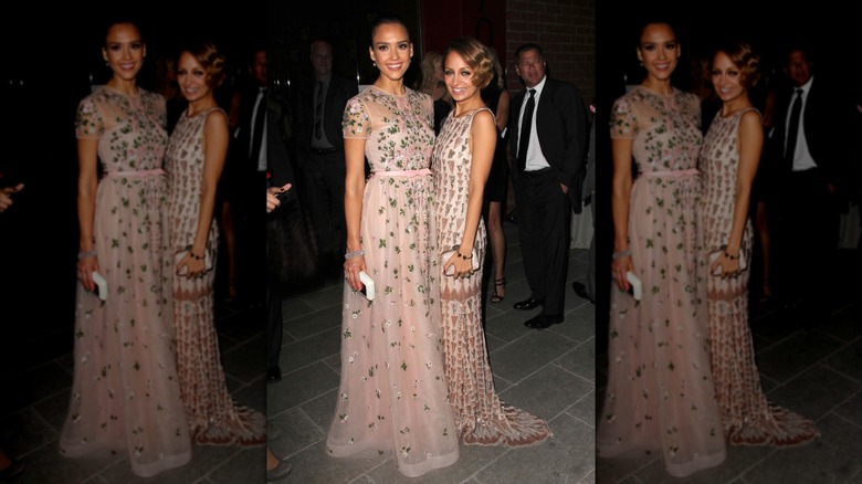 Jessica Alba and Nicole Richie smiling as they're both wearing pink-toned, floor-length gowns