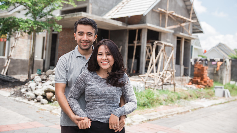 couple stands near new home