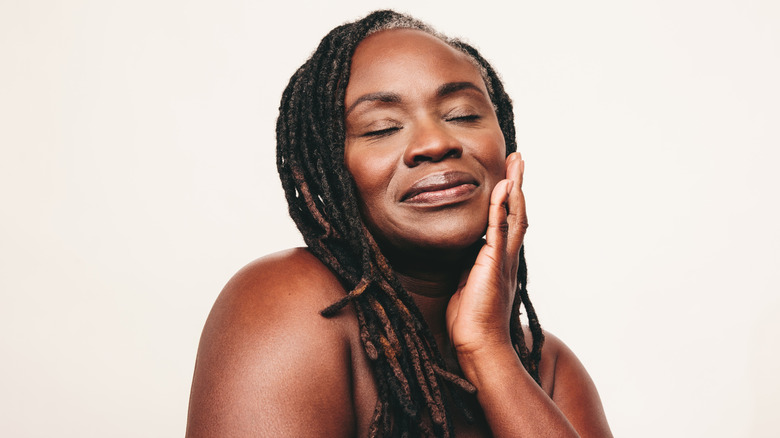 Mature woman with eyes closed and her hand on her cheek