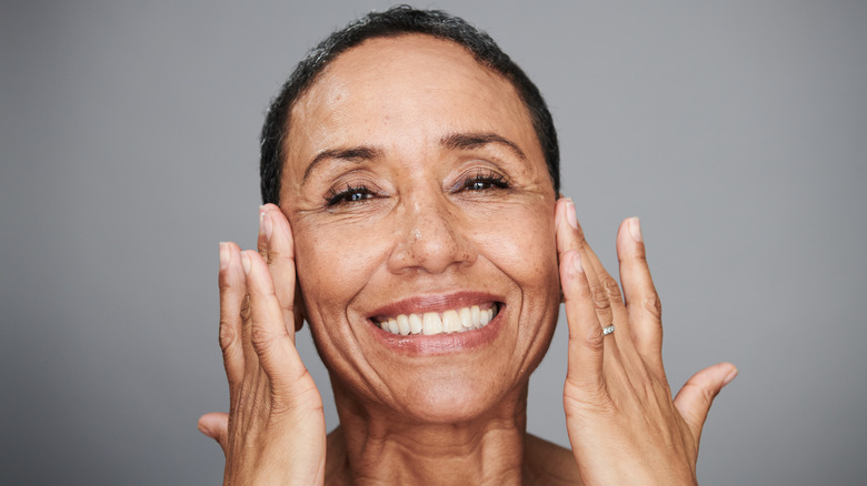 Mature woman smiling and touching her cheeks