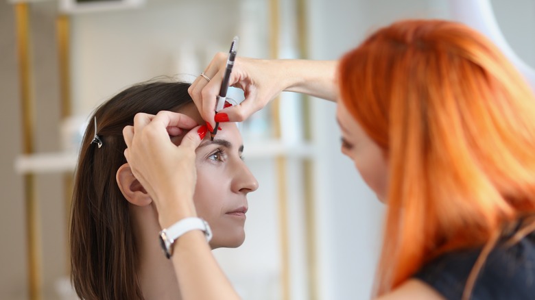 woman applying eyebrow pen to woman