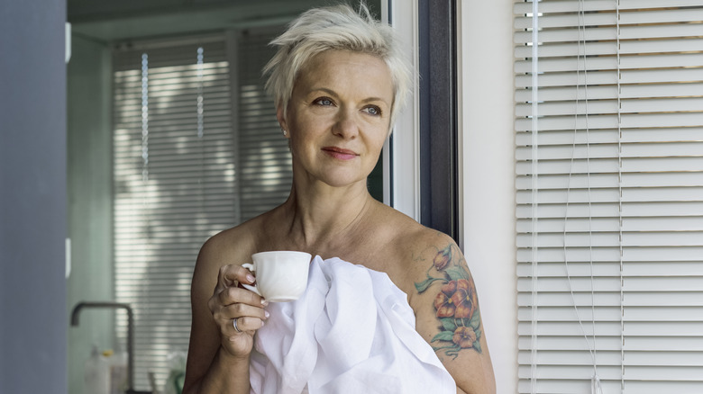 Older woman with tattooed arm drinking coffee