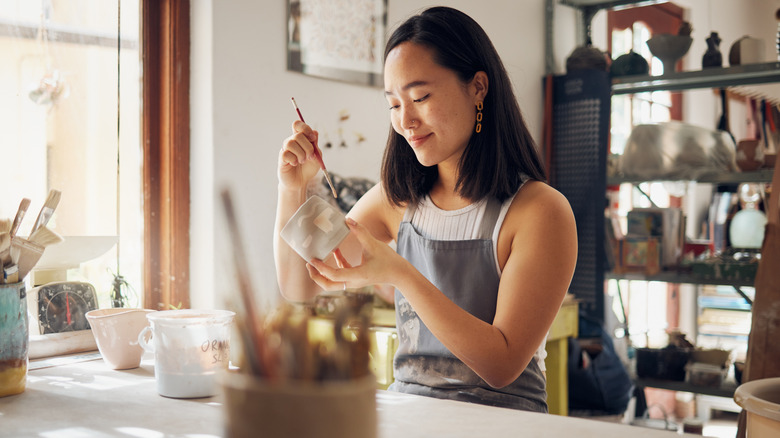 Woman glazing mug in a pottery studio