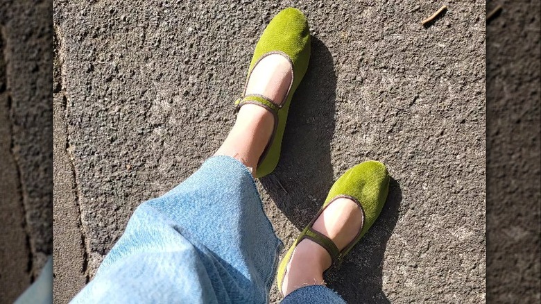 Closeup of feet on pavement wearing green mary janes