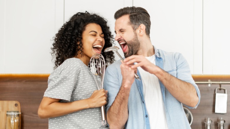Couple dancing in kitchen with utensils
