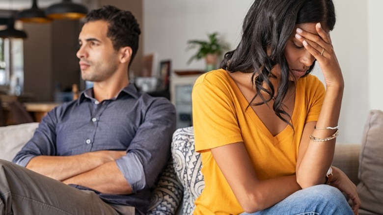 Couple sitting on couch, looking away after arguing