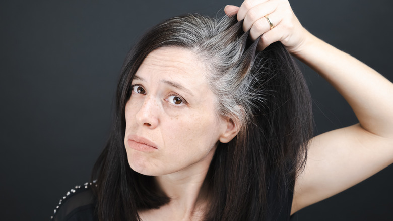 A woman grabs a hold of her hair and seems to examine it