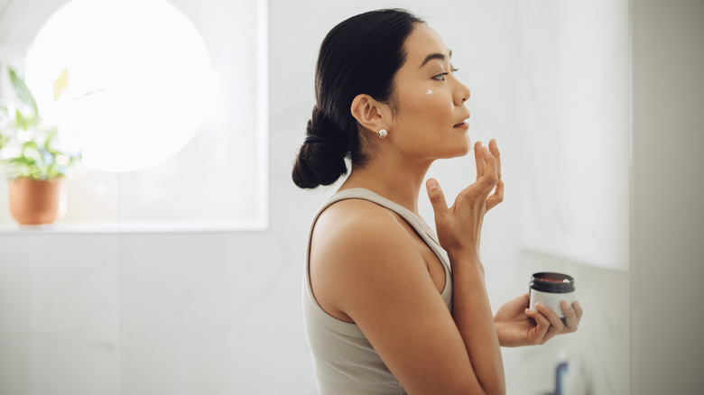 A woman applying moisturizer to her skin