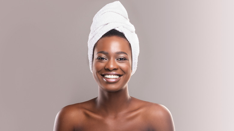 Woman wearing white towel on head smiling.
