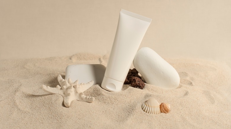 Bottle of sunscreen in sand