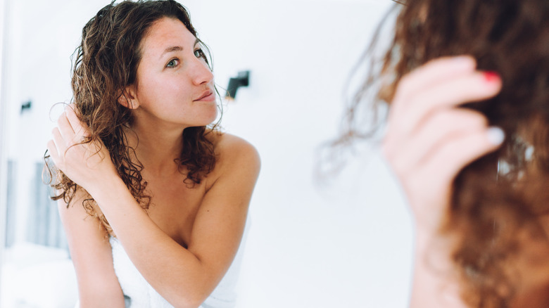 Woman crumples hair in front of mirror