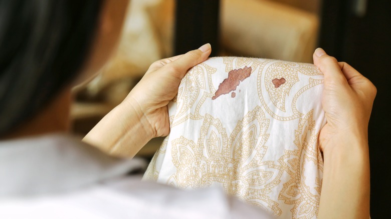 A person inspecting a blood stain on their sheets