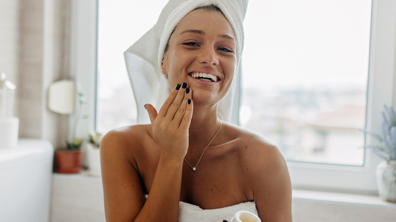 woman in towel applying lotion