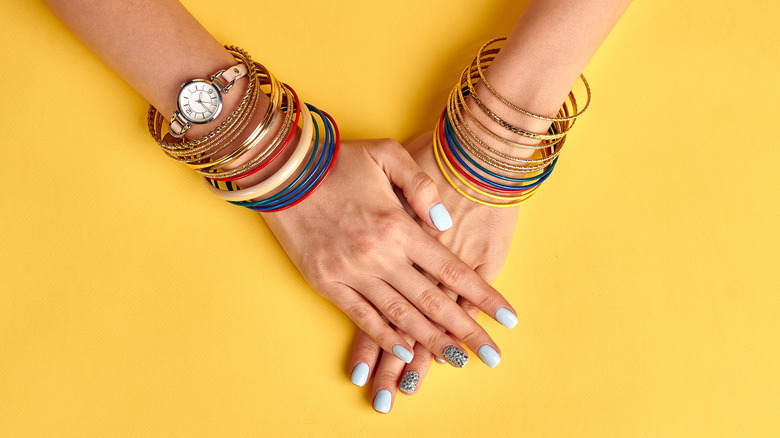 woman wearing watch and bracelets against yellow background