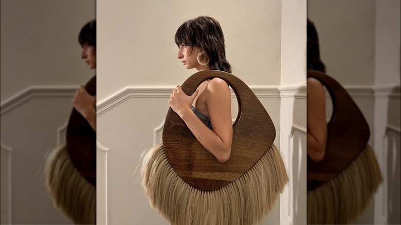 woman posing with wooden bag